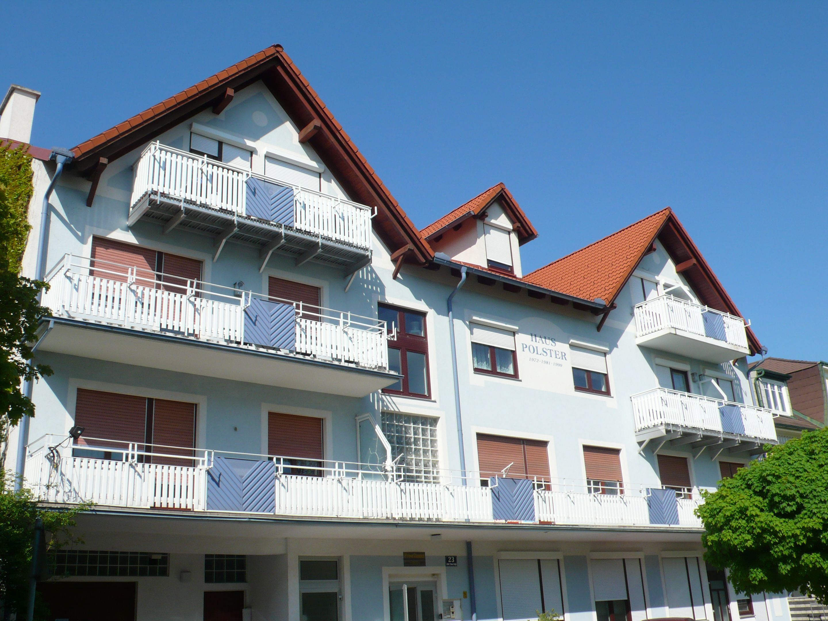 Mehrstöckiges Gebäude mit blauer Fassade und roten Dächern.