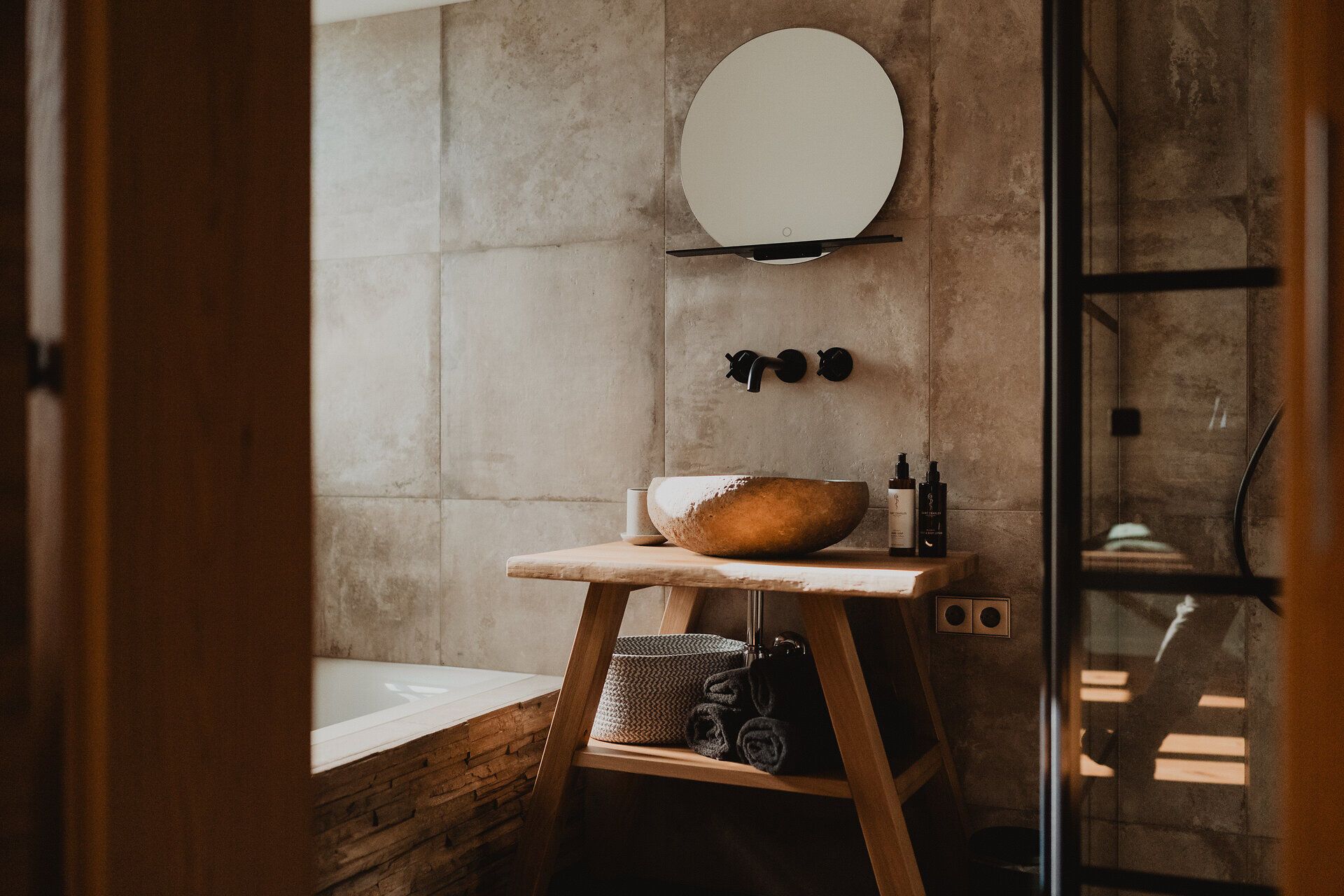 Badezimmer, mit einem Waschtisch aus Holz mit einer Schale als Waschbecken und Armaturen an der Wand 