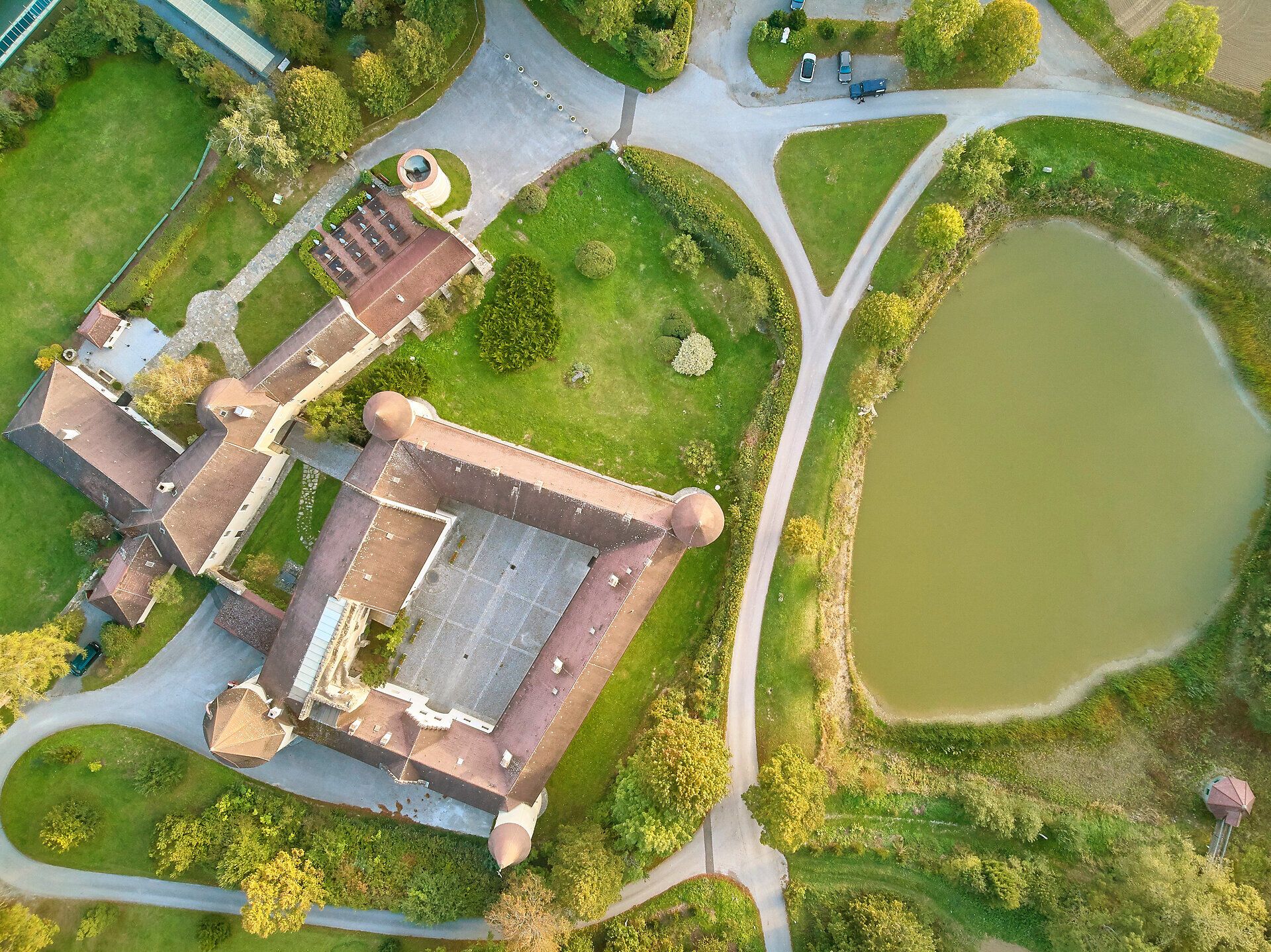 Luftaufnahme von Schloss Waldreichs mit umliegendem Park und Teich.