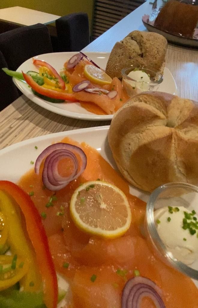 Frühstücksteller mit Lachs, Zwiebeln, Zitrone, Paprika und Brötchen.