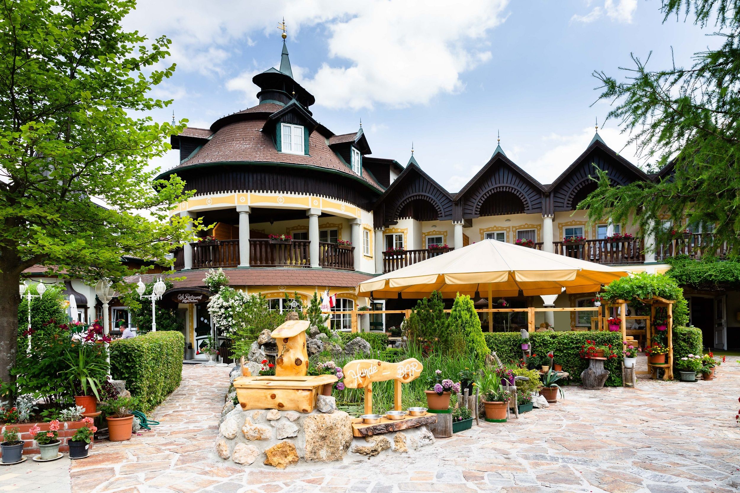 Ein traditionelles Gebäude mit Holzbalkonen und einem Garten voller Pflanzen und Blumen.