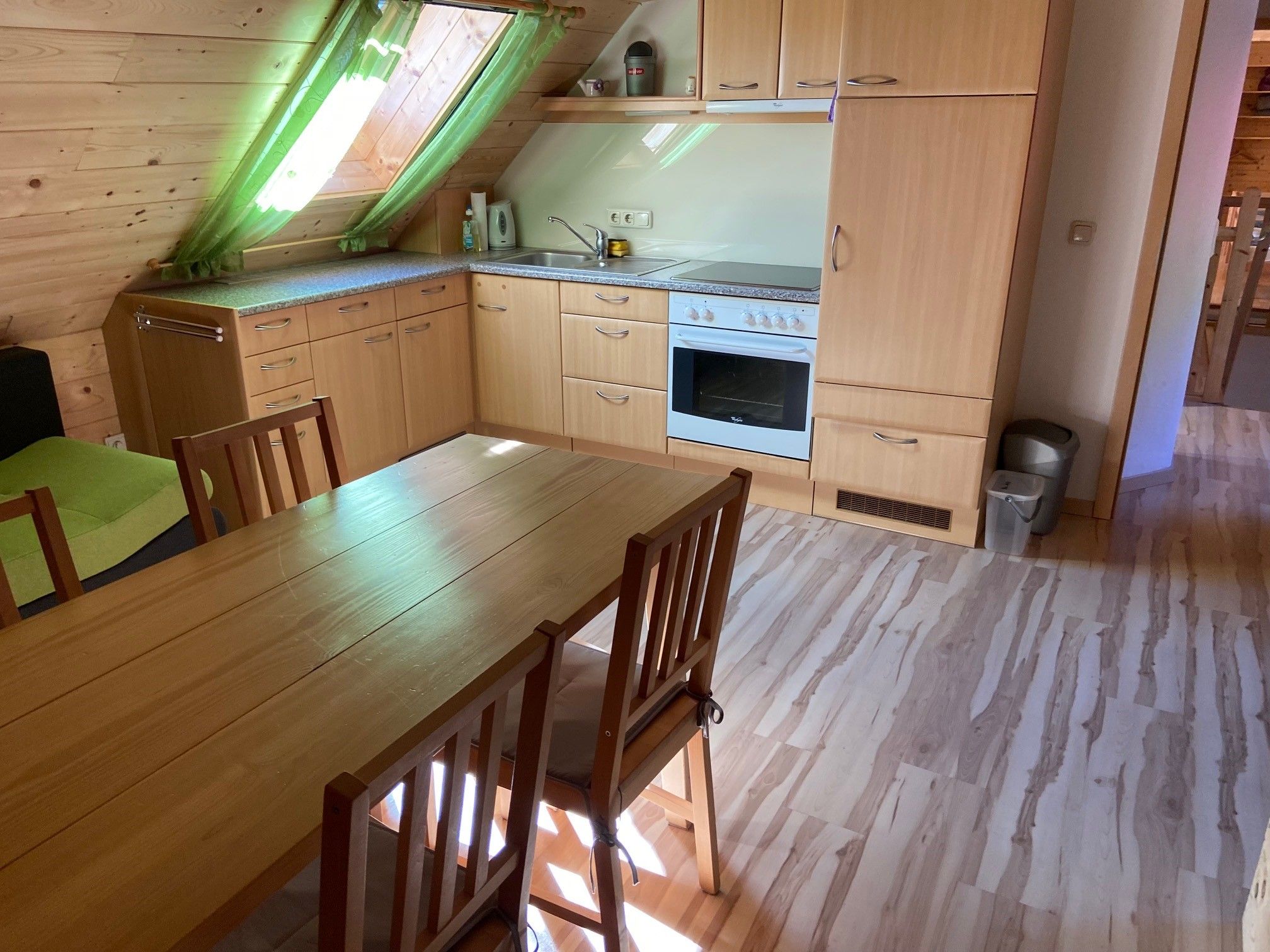 Küche in einer Ferienwohnung mit Holzmöbeln und Dachfenster.
