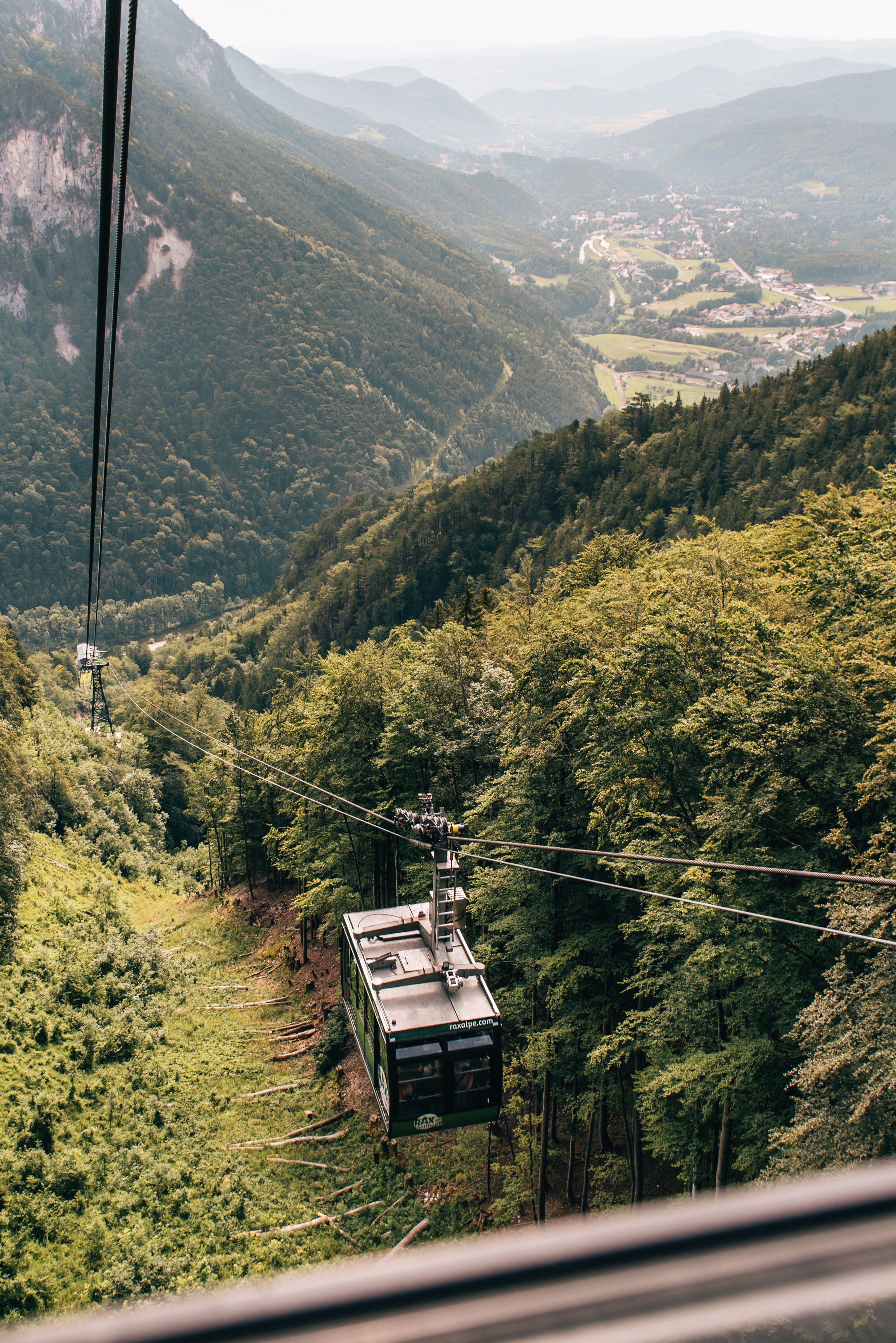 Seilbahn in den Bergen mit Blick auf bewaldete Hänge und Täler.