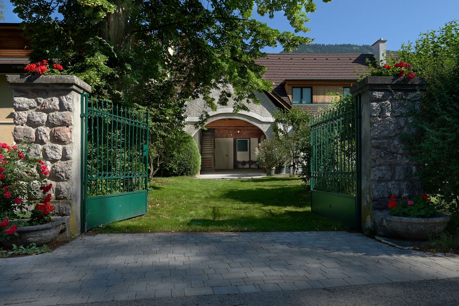 Offenes grünes Tor führt zu einem Haus mit Garten.