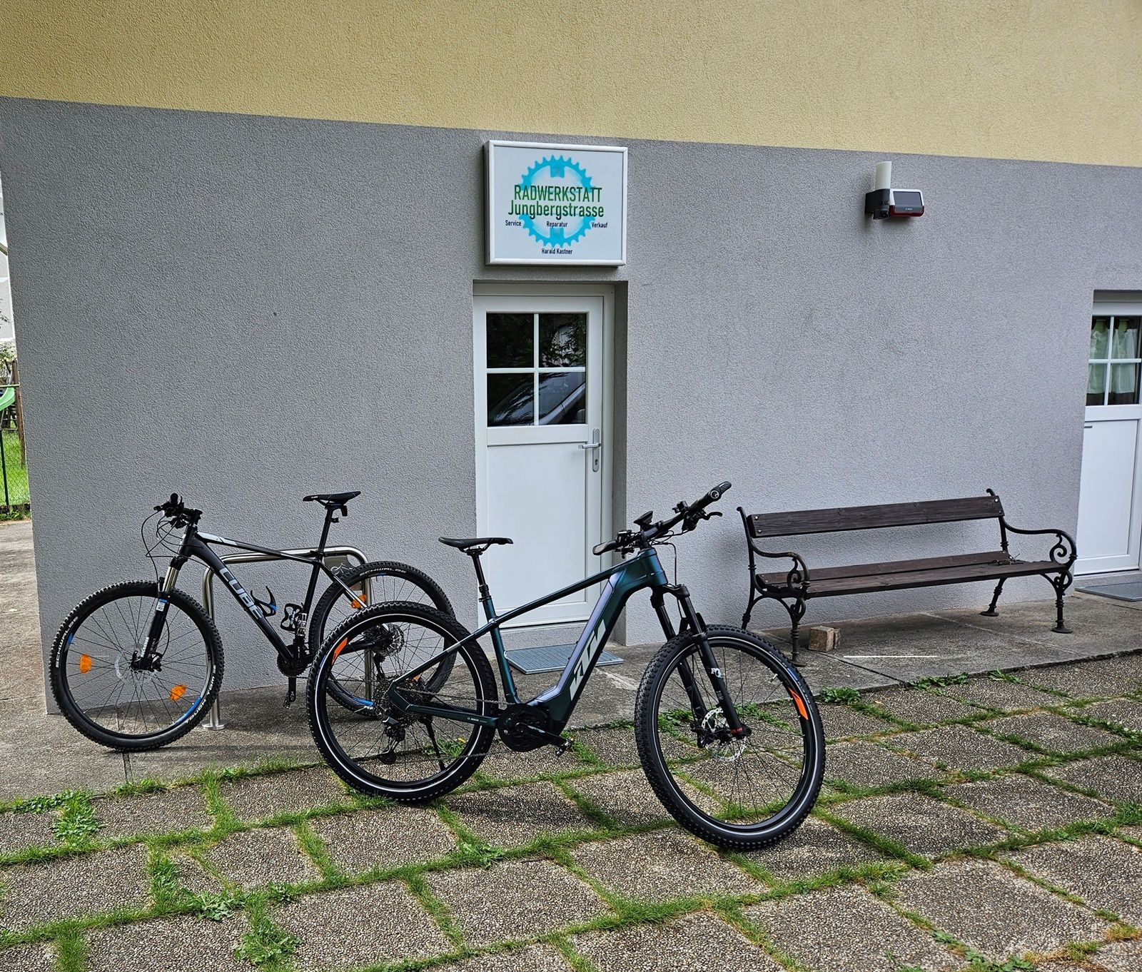 Zwei Fahrräder vor einer Werkstatt mit Schild 'Radwerkstatt Jungbergstrasse'.