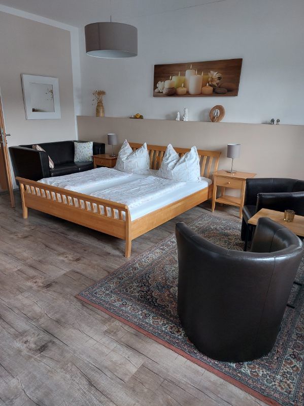 Gemütliches Gästezimmer mit Doppelbett, Ledersesseln und dekorativem Bild an der Wand.