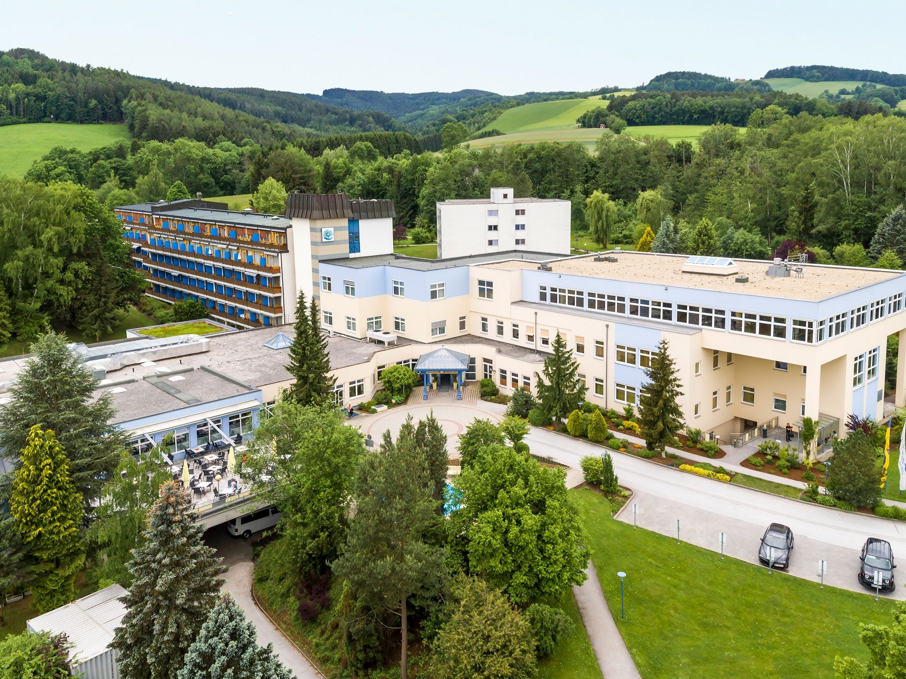 Luftaufnahme eines großen Gebäudekomplexes in einer grünen Landschaft.