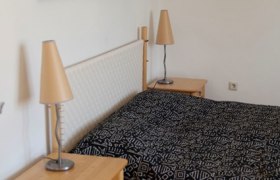 Schlafzimmer mit Doppelbett, Nachttischen und Wandbildern.