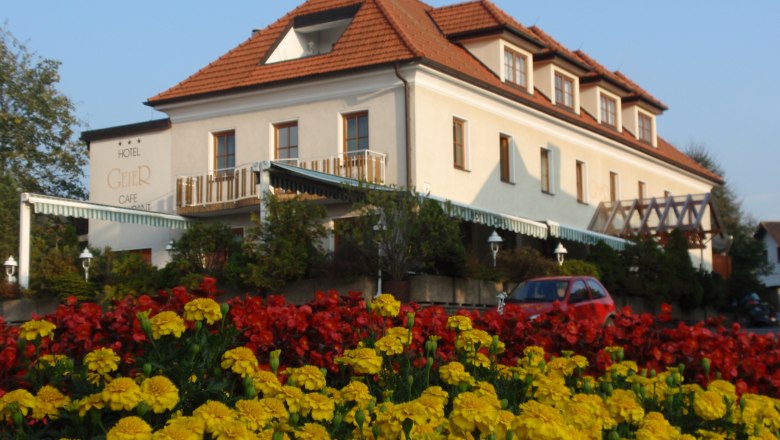Hotel Geier in Bad Sch&ouml;nau mit Blumenbeet im Vordergrund.