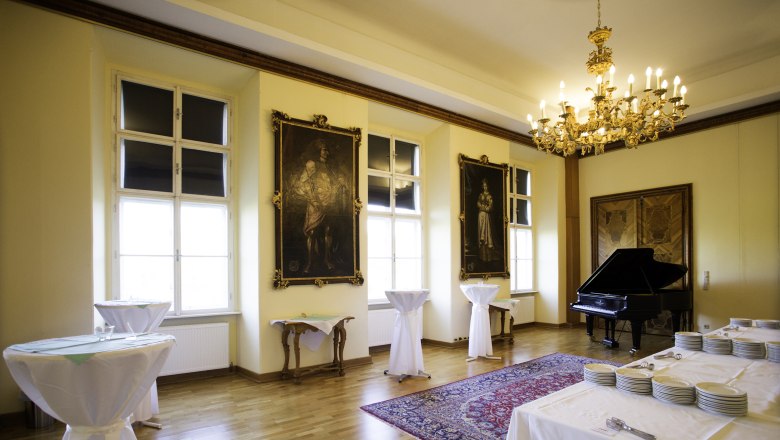 Prunkvoller Raum mit fl&uuml;gel und hohen Fenster, vor dem Stehtische platziert wurden
