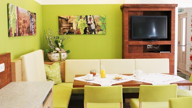 Gem&uuml;tlicher Essbereich mit gr&uuml;nen W&auml;nden, Holzm&ouml;beln und einem Fernseher.