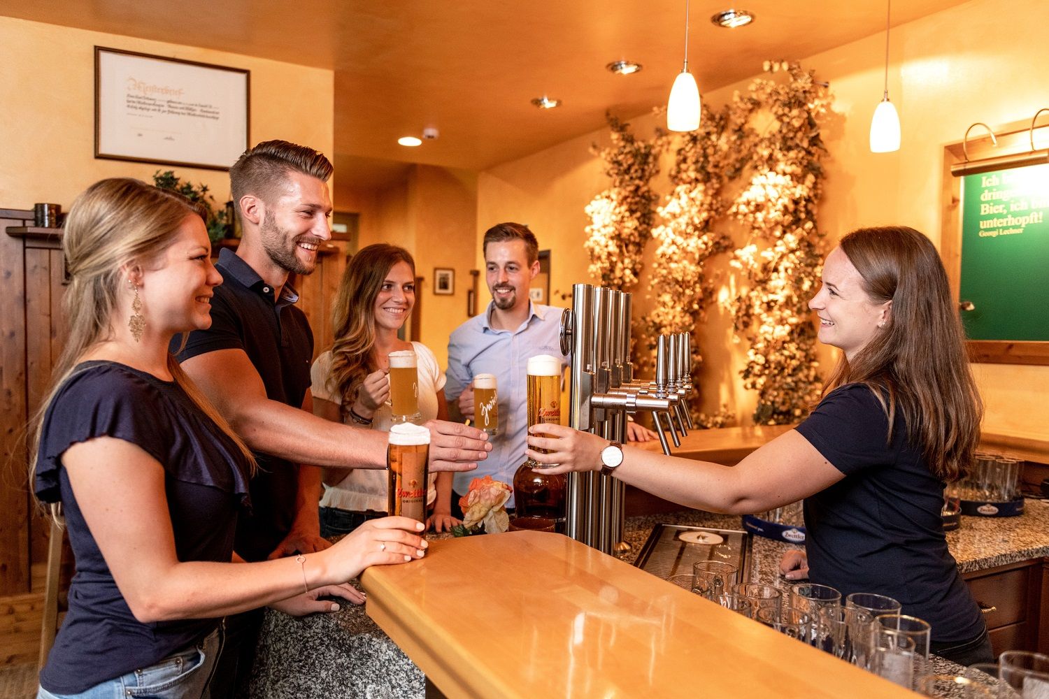 Gruppe von Menschen in einer Bar, die Biergläser anstoßen.