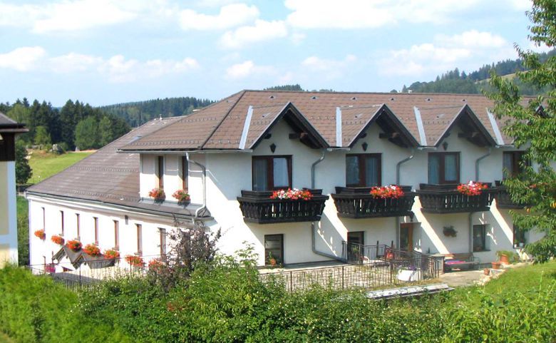 Ein großes, weißes Gebäude mit braunen Dächern und Balkonen mit Blumen.