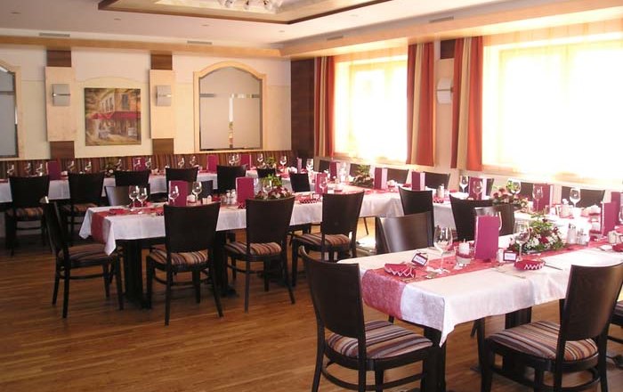 Speisesaal_neu, © Kerschbaummayr Ein elegant gedeckter Speisesaal mit mehreren Tischen, roten Tischläufern und Stühlen.