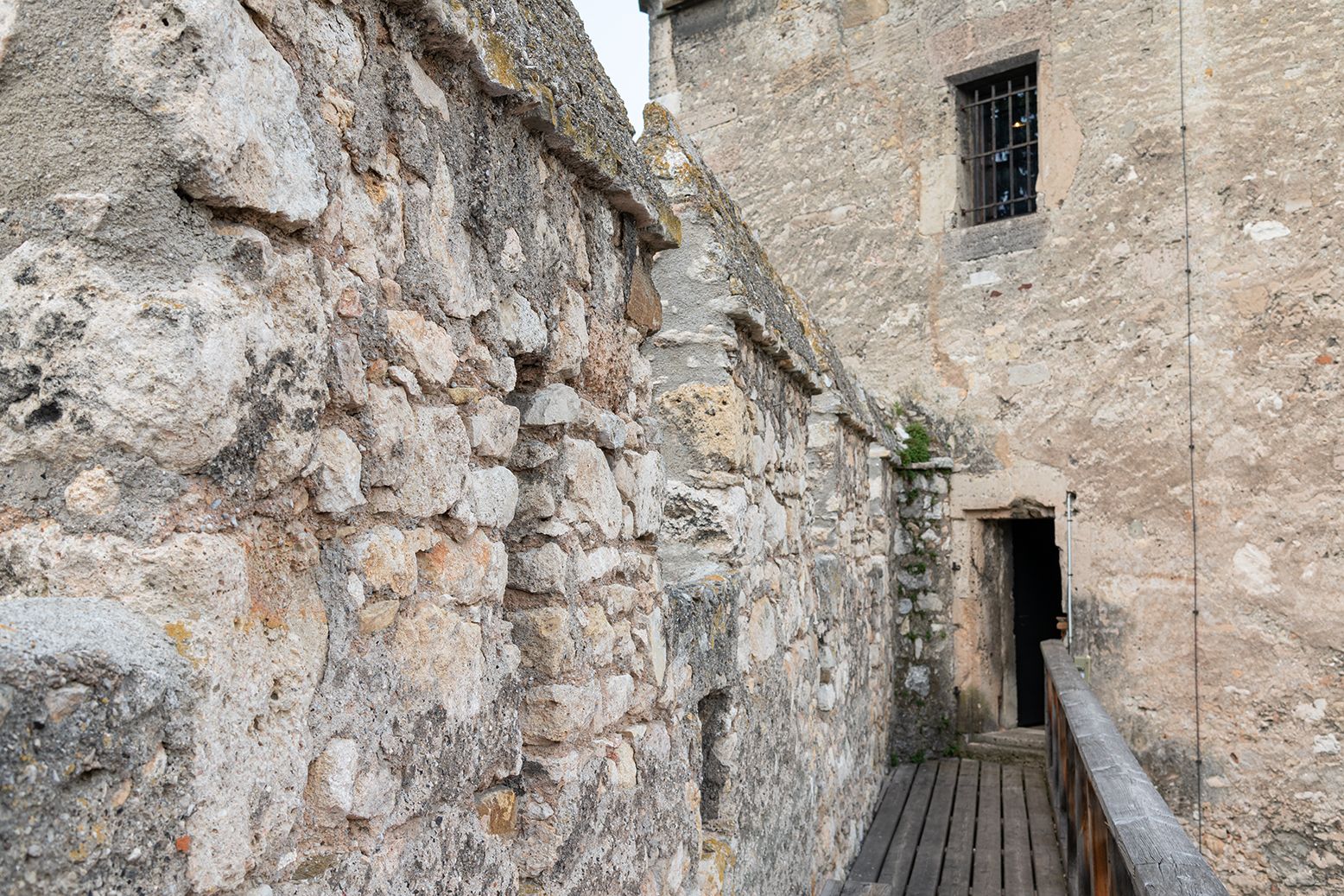 Steinerne Stadtmauer mit Holzboden und Tür.