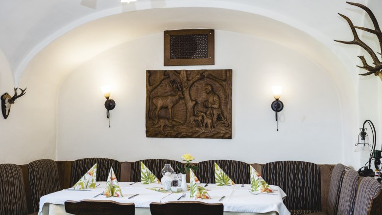 Gemütlicher Gastraum mit Holztäfelung und Jagdmotiven an der Wand.