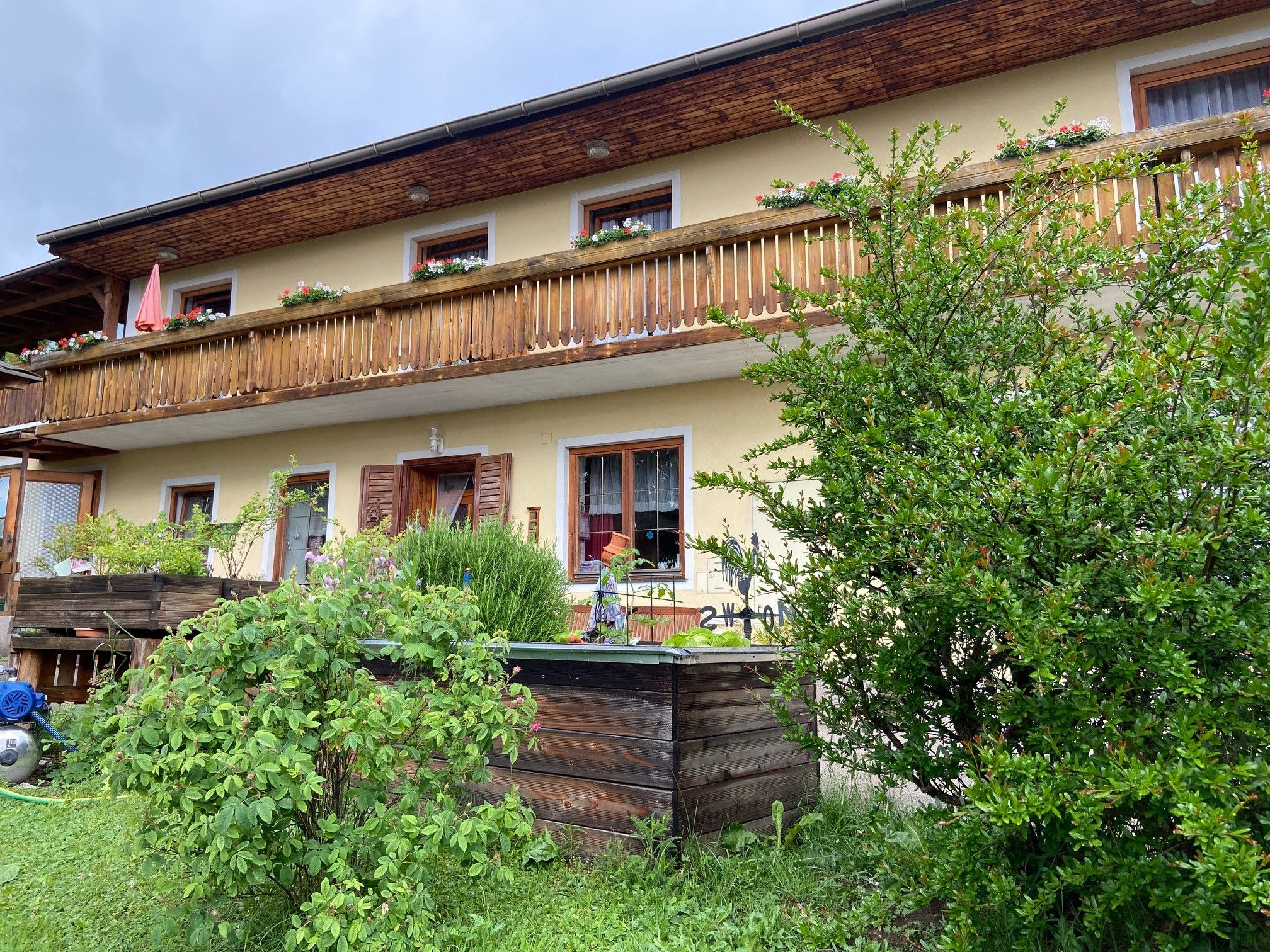 Zweistöckiges Haus mit Holzbalkon und Garten.