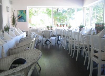 Ein heller Wintergarten mit weißen Möbeln und großen Fenstern.