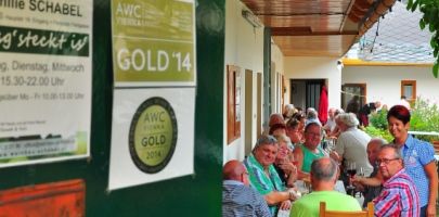 Menschen sitzen an einem langen Tisch in einem überdachten Außenbereich eines Restaurants.