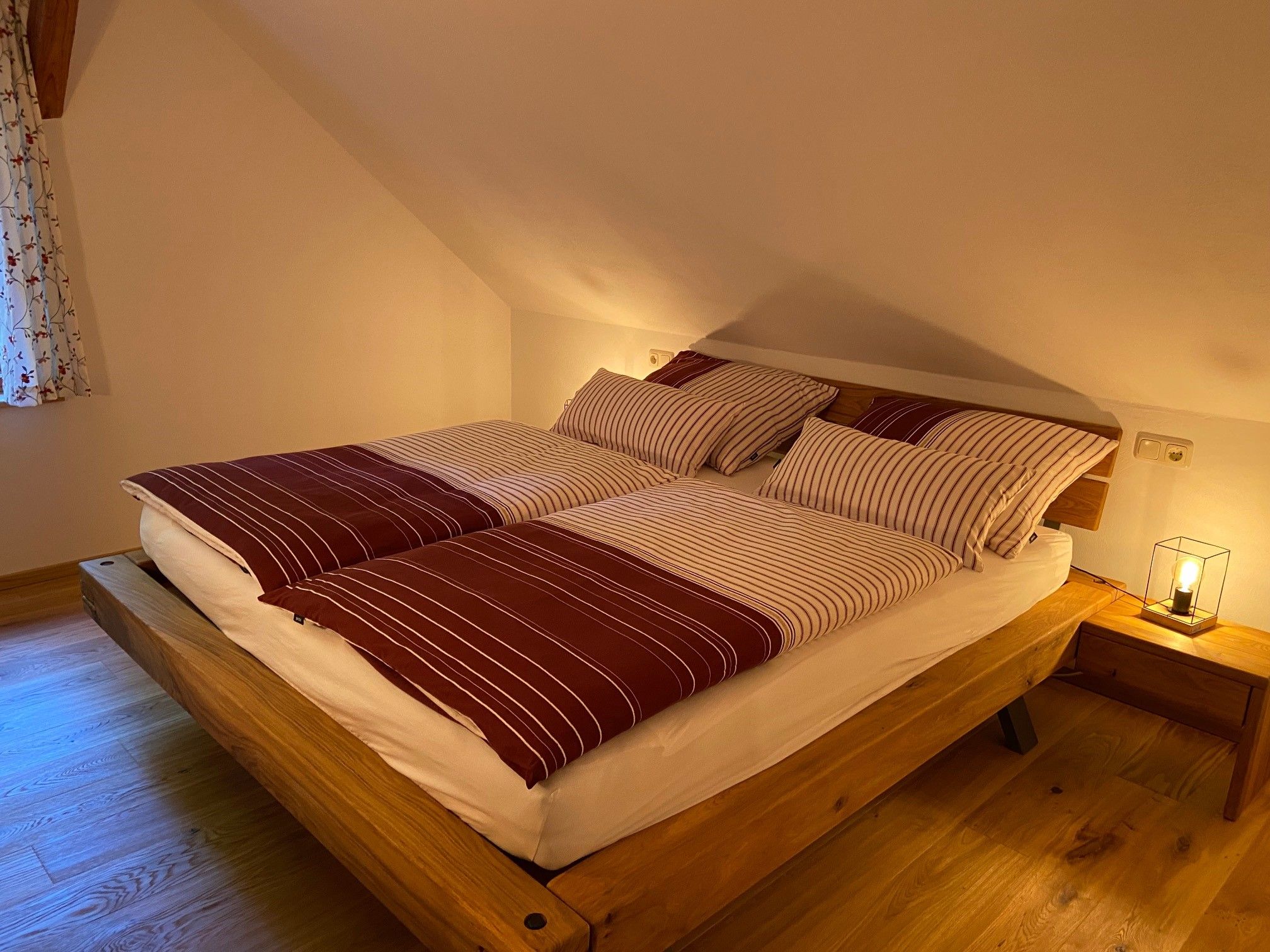 Gemütliches Doppelzimmer mit Holzbett und gestreifter Bettwäsche.