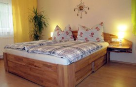 Gem&uuml;tliches Schlafzimmer mit Doppelbett, Pflanzen und Wanddekoration.