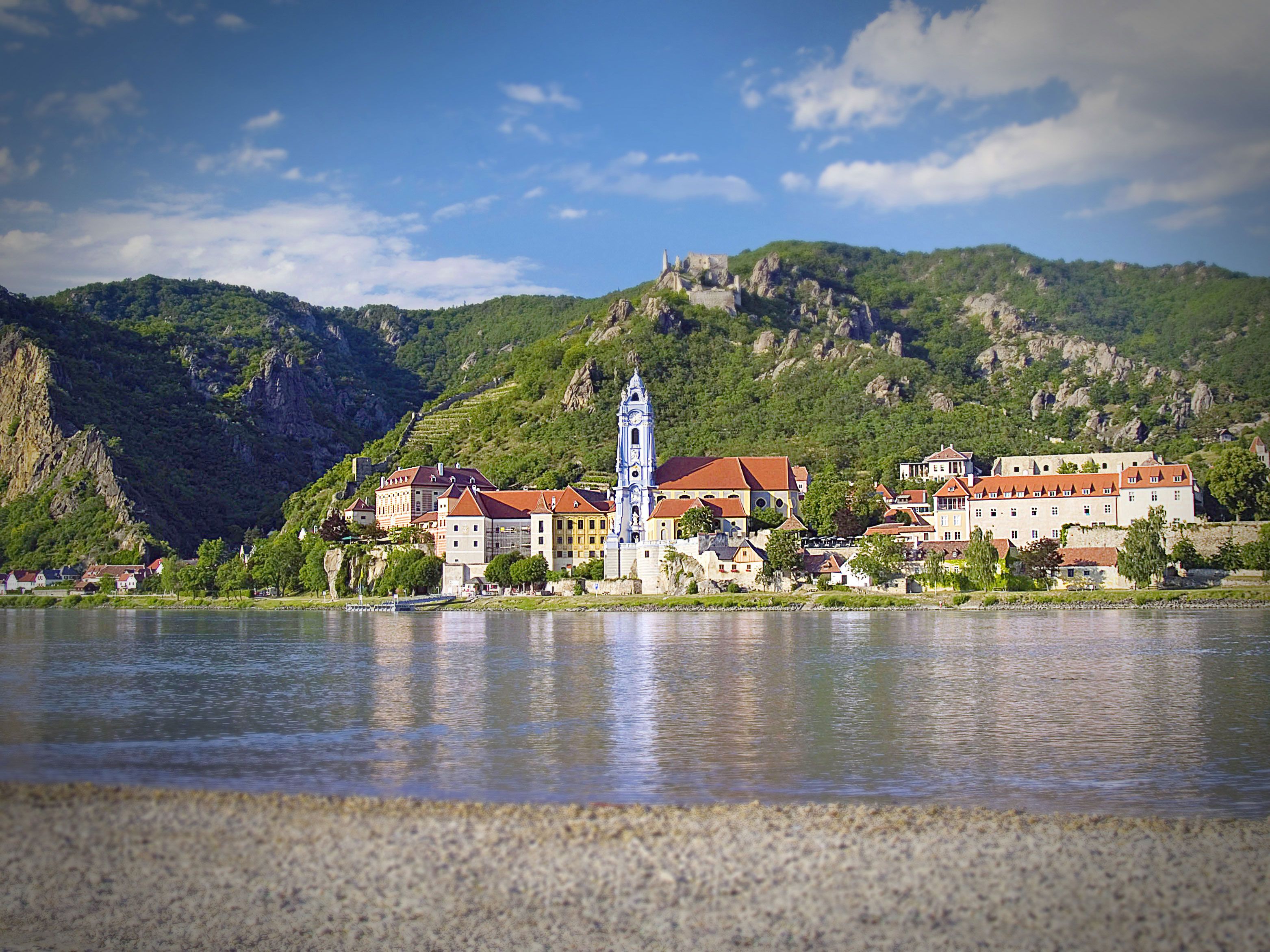 Blick auf Dürnstein mit der blauen Kirche und der Donau im Vordergrund.