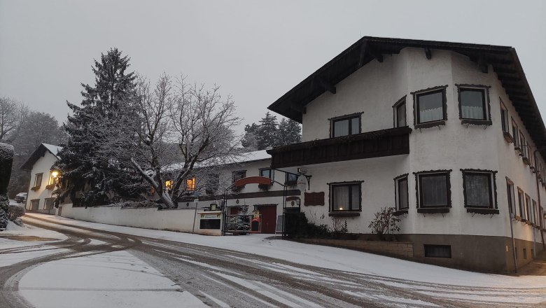TDR-WelserhofWinter, © Nora Bartfai Verschneite Straße mit Gebäuden im Winter, beleuchtete Fenster.