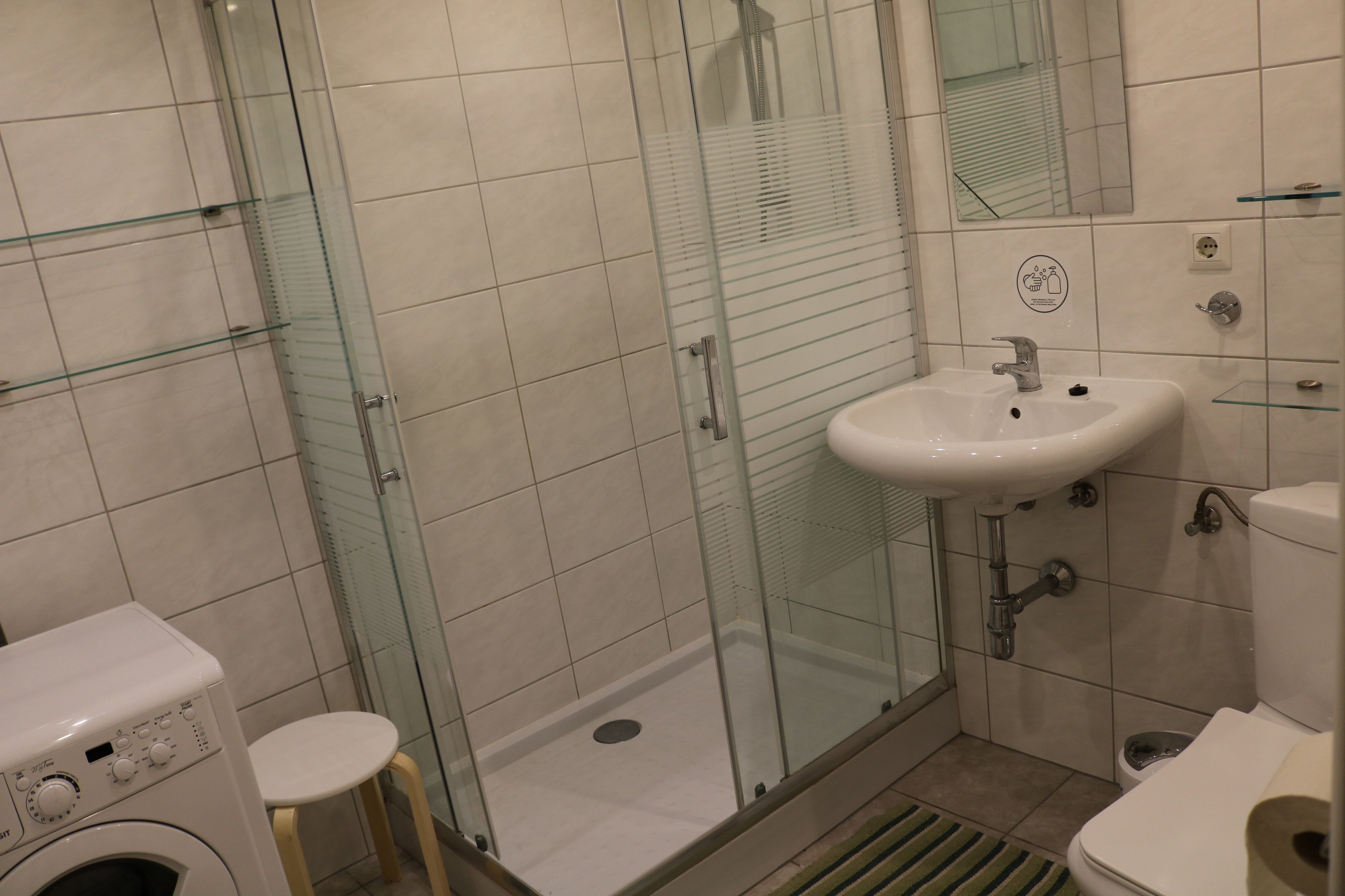 Modernes Badezimmer mit Dusche, Waschbecken, Toilette und Waschmaschine.