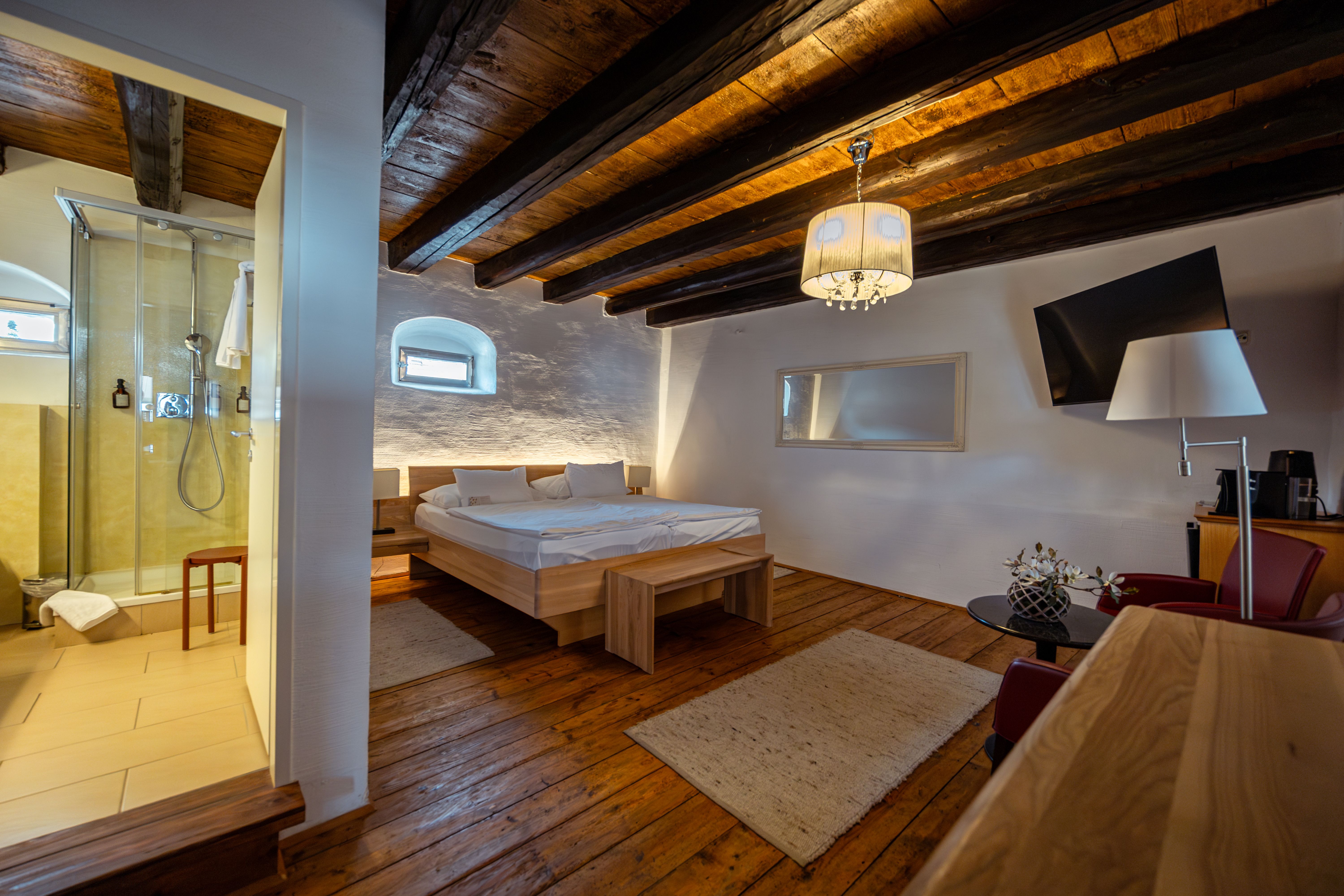 Ein Innenhof mit Kopfsteinpflaster, Tischen und Stühlen, umgeben von Gebäuden mit Arkaden und einem modernen Balkon.