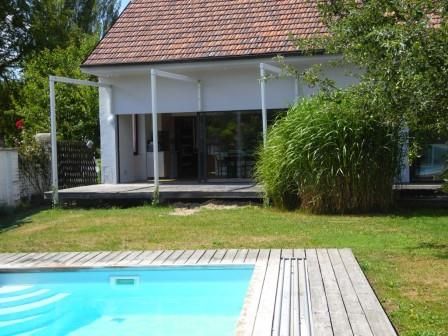 Ein modernes Haus mit Terrasse und Pool im Garten.