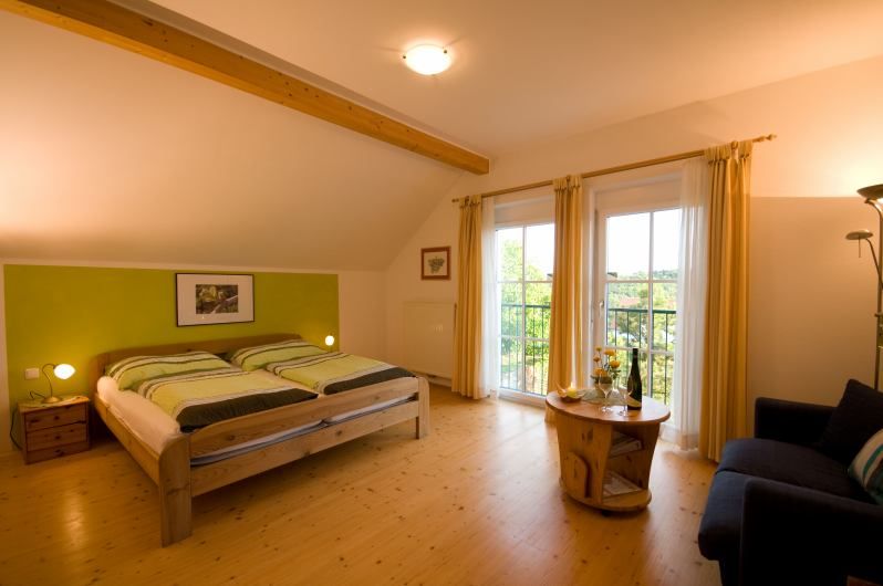 Gemütliches Schlafzimmer mit Doppelbett, Holzmöbeln und Balkonzugang.