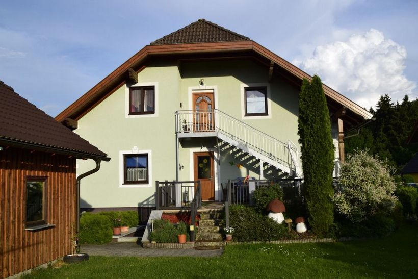 Ein zweistöckiges Haus mit grünem Anstrich und einer Außentreppe im Garten.