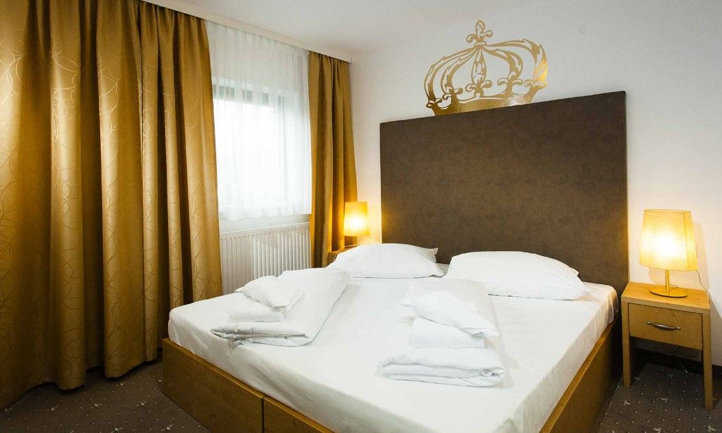 Ein Doppelzimmer mit einem großen Bett, goldenen Vorhängen und zwei Nachttischen mit Lampen.