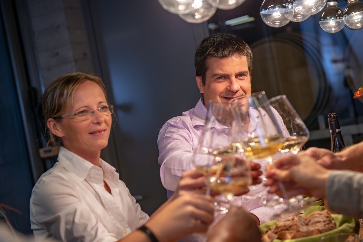 Menschen stoßen mit Weingläsern an einem Tisch an.