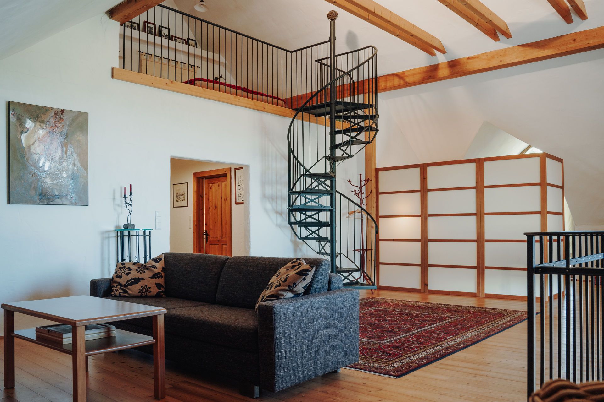 Wendeltreppe hinauf zum Schlafbereich, im Vordergrund gemütliche Couch