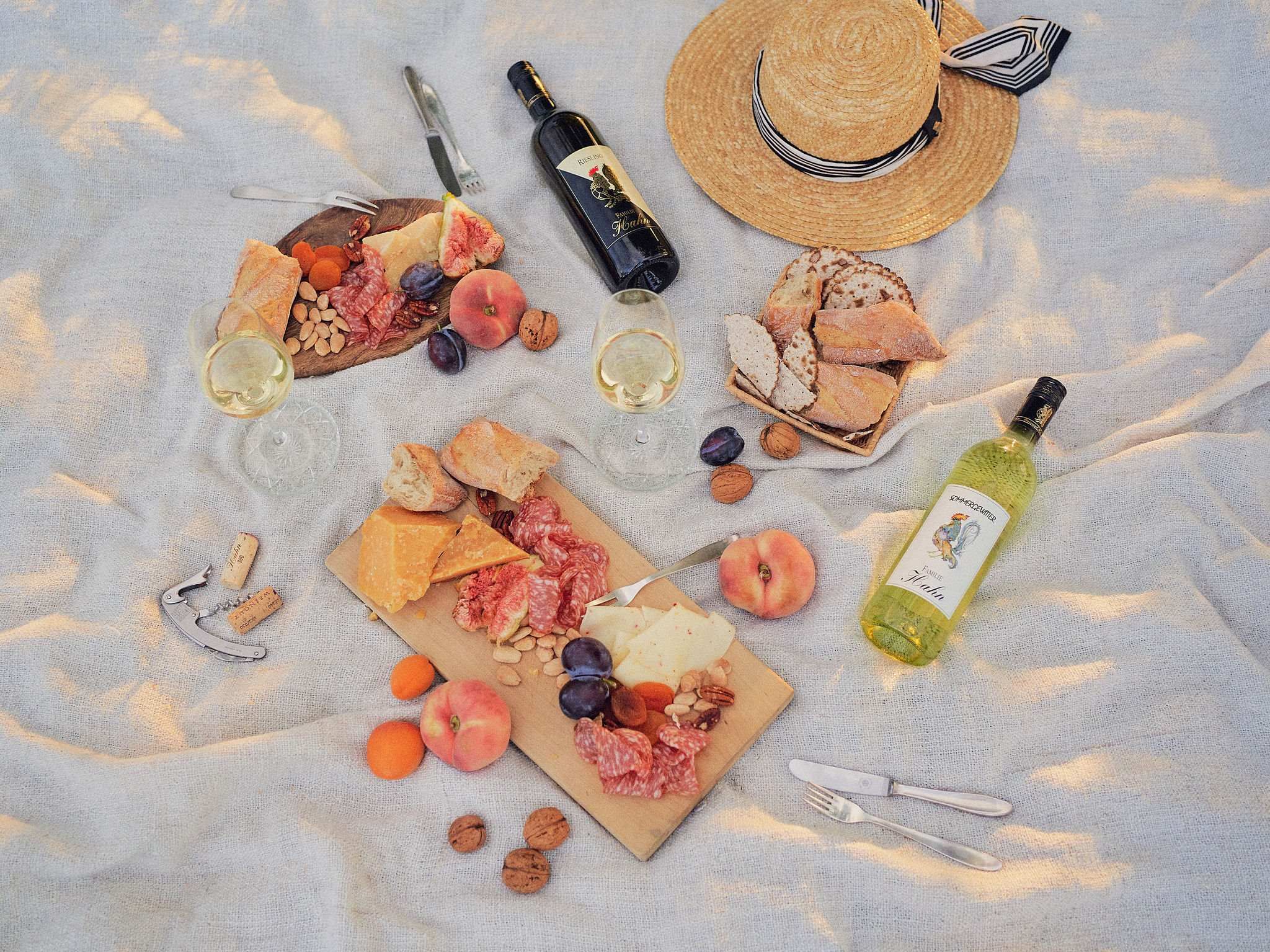 Picknick mit Wein, Käse, Brot und Früchten auf einer Decke.