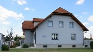 Au&szlig;enansicht eines grauen Hauses mit rotem Dach und mehreren Fenstern.