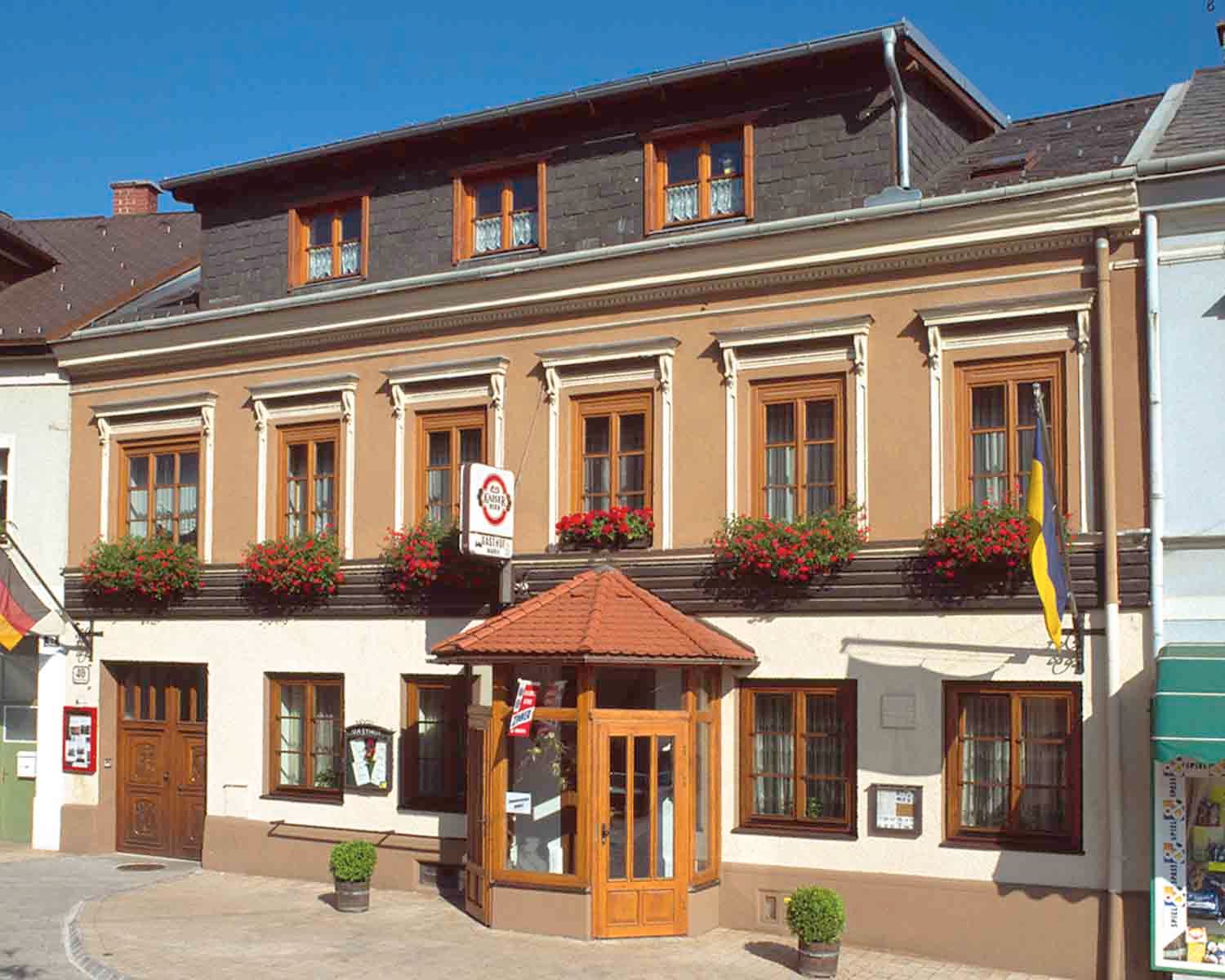 Traditionelles Gasthaus mit Blumen und Fahnen.