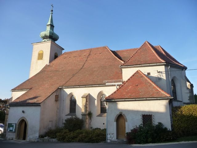 Historische Kirche mit rotem Ziegeldach und kleinem Turm mit grünem Dach.
