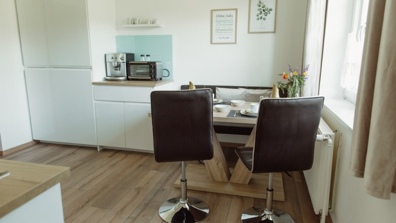 Moderne Küche mit Esstisch, Stühlen und Geräten.