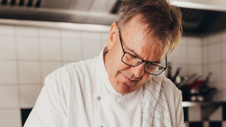 Ein Koch in weißer Uniform arbeitet konzentriert in einer Küche.