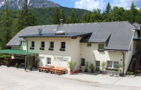 Berggasthof Mamauwiese vor bewaldeten Bergen.
