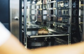 Ein St&uuml;ck Fleisch mit Kr&auml;utern in einem professionellen Ofen.