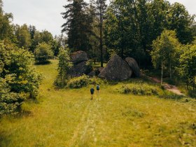 Zwei Personen gehen auf die Steinformationen in der Blockheide zu
