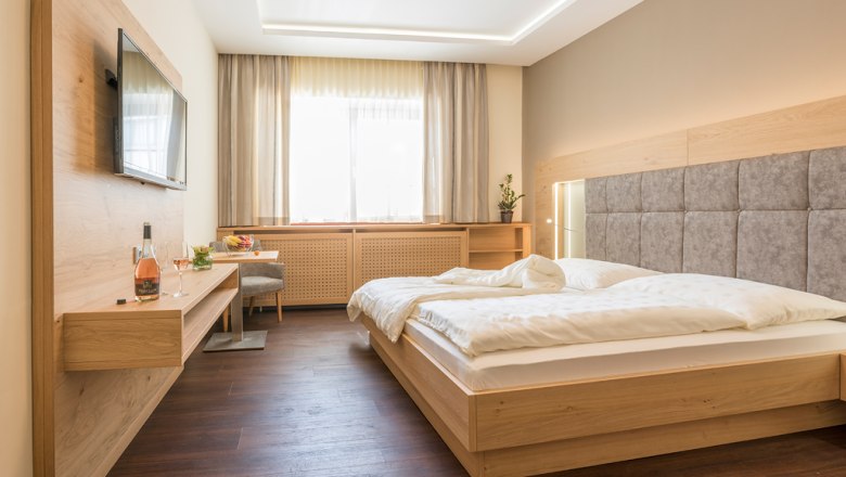 Modernes G&auml;stezimmer mit Doppelbett, Flachbildfernseher und Holzm&ouml;beln.