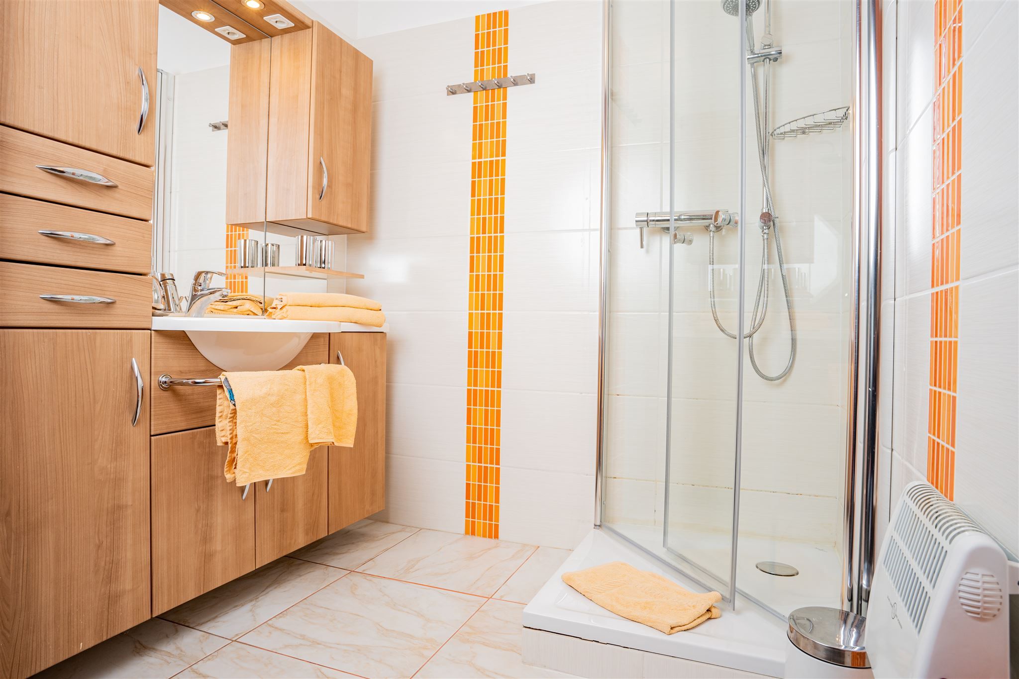 Modernes Badezimmer mit Holzmöbeln, Dusche und orangefarbenen Akzenten.