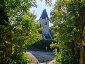 Schattiger Hohlweg, im Hintergrund eine Kirche