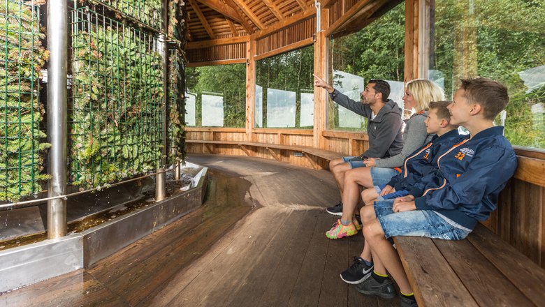 Familie sitzt in einem Holzpavillon vor einer Saline.