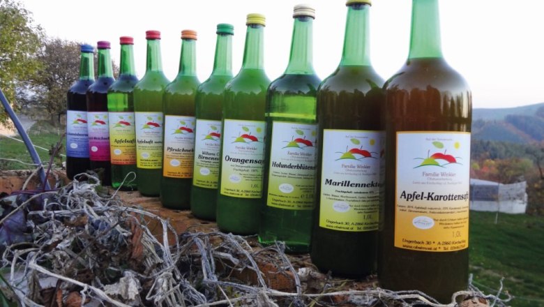 Eine Reihe von verschiedenen Fruchtsaftflaschen auf einem Holzbalken im Freien.