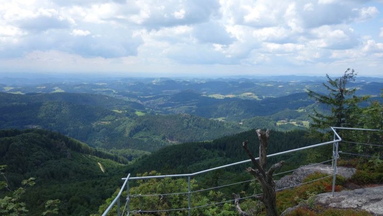 Aussicht von der Burgsteinmauer &uuml;ber bewaldete H&uuml;gel und T&auml;ler unter einem bew&ouml;lkten Himmel.
